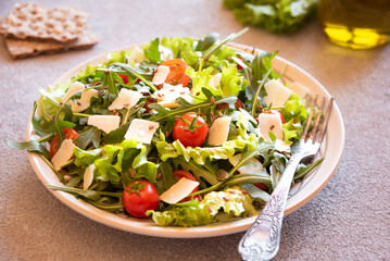 Fresh vegetable salad with tomatoes, arugola, parmesan cheese and other ingredients, healthy eating