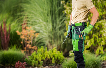 Landscaping and Gardening Worker with His Tools Staying Inside Backyard Garden