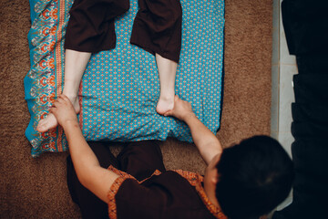 Fototapeta premium Thai man making classical thai massage procedure to young woman at beauty spa salon