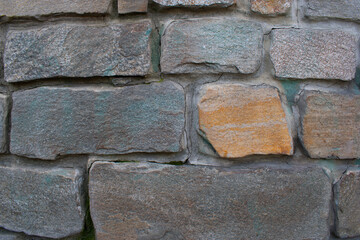 Wall decor with colorful natural stones. Stone masonry on a rounded surface. Interior and decor. Abstraction, texture, background, vintage.