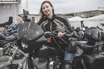 Plakat A happy young woman is sitting on a motorcycle and smiling. Motorcycle riding, lifestyle, biker movement.