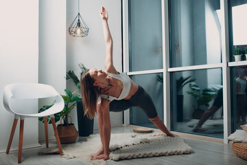 Adult mature woman doing yoga at home living room.
