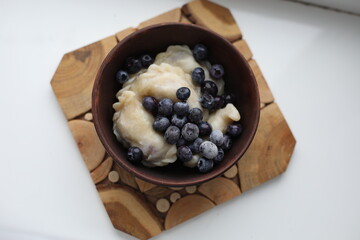dumplings with blueberries on wooden plate
