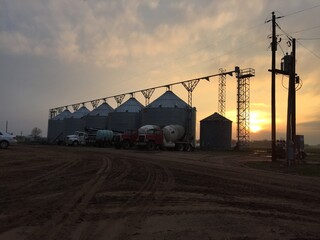 Fototapeta premium sunset farm, harvest storage, grain bins, producing feed
