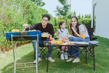 Asian Family Enjoying Camping Holiday In the backyard at home,  Happy family having barbecue with grill outdoors