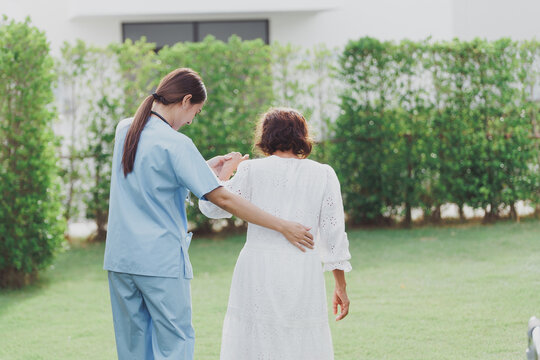 Asian young woman nurse at nursing home take care, patient and woman nurse  walk in the park, man caregiver helping patient, Happiness Asian family concepts