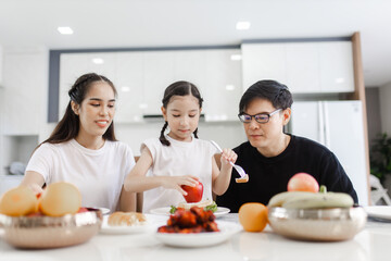 Asian family having meals together and showing thumbs up at home happily, Happy young parents are having fun with their little daughter during lunch at the dining table.