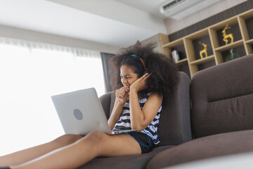 Excited cheerful young Black woman using laptop computer on sofa at home, feeling joy, singing, laughing, happy time,  Cute little Girl Study At Home With Laptop And Headphones, Relax concept