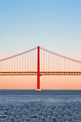 Obraz premium Iconic orange red suspension bridge over Tagus River in Lisbon, Portugal. 25 de Abril Bridge, 25th of April Bridge at golden hour sunset. Copy space, place your text.
