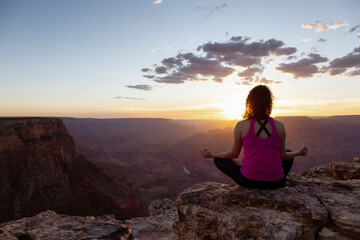 Naklejka na ściany i meble Adventurous Traveler woman doing meditation on Desert Rocky Mountain American Landscape. Cloudy Sunny Sky. Grand Canyon National Park, Arizona, United States. Adventure Travel
