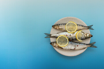 Fresh sardines, lemon and salt on kitchen, close up shot. Creative fish. Fish is widely used in the cuisines of Greece, Spain and Italy, top view 
