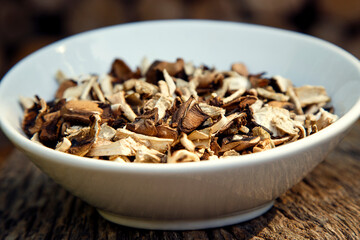 Dried natural porcini mushrooms in a plate. White mushrooms in a bowl on a wooden background. The concept of vegetarianism, restaurants, healthy eating.