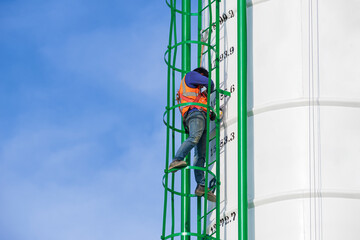 Low angle view of maintenance worker with safety equipment is repairing metal stairs on concrete...