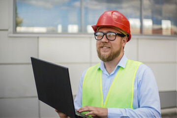 smiling engineer entering data into laptop