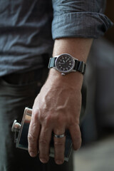 Pilot's watch on man's wrist with flask