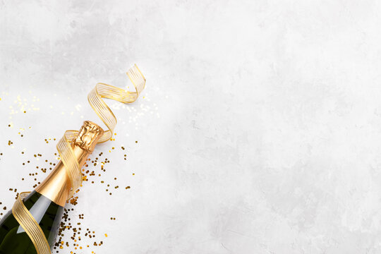 Flat lay composition of Champagne bottle and confetti on grey stone background copy space