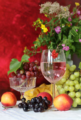 Glass of pink wine, grapes, berries and flowers on a table. Delicious summer food close up photo. Textured background with copy space.