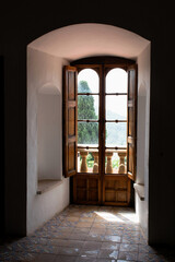 Vintage european interior, Arched corner with window, balcony entrance and wooden shutters. interior design. Historic manor with mosaic tile floor and white walls. Romantic antique residence.
