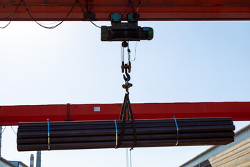 Gantry crane transporting stack of metal pipes