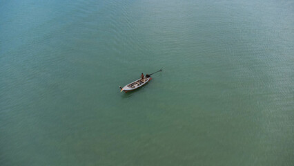 Aerial view from a drone of Thai traditional longtail fishing boats sailing in the sea. Top view of a fishing boat in the ocean.