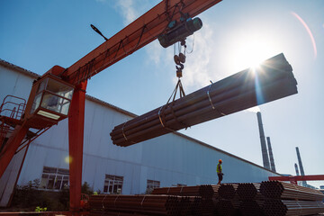 Gantry crane transporting stack of metal pipes