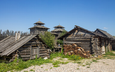 The ancient Shchurovskoye settlement in Suzdal in Russia with medieval wooden buildings among the bright green foliage of trees and blue clear sky on a sunny summer day