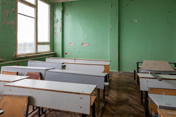 A fragment of the interior of a classroom with desks in need of repair