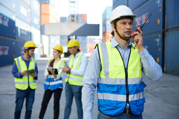 factory worker or engineer using walkie talkie and talking about work in containers warehouse storage