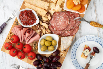 Appetizer board with cheese, nuts, fruits, toasts and charcuterie over wooden table