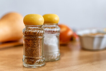 Glass salt and pepper shakers on wooden board.