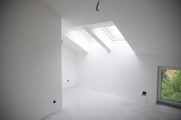 modern attic construction site freshly painted, the floor is still screed, walls are white