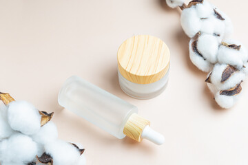 Moisturizer cream jar, serum in glass frosted bottle on beige background with copy space. Set for skin and body care beauty products. unbranded package