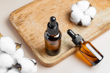 Dark amber glass dropper bottles mockup. Natural organic essential oil packaging design. dry cotton flowers and beige background and wooden tray