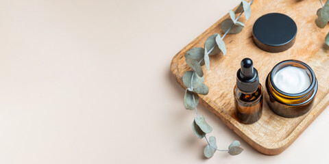 Set of amber glass cosmetic bottles on wooden tray. dropper bottle and cream jar package. Skincare beauty products packaging design for daily routine