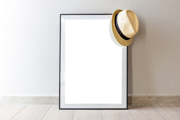 picture frame leaning against the wall with a sun hat on the corner
