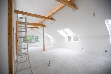 modern attic construction site freshly painted, the floor is still screed, walls are white