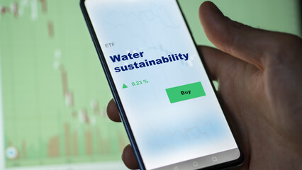 An investor's analyzing the water sustainability etf fund on screen. A phone shows the ETF's prices stocks to invest