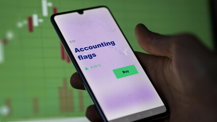 An investor's analyzing the accounting flags etf fund on screen. A phone shows the ETF's prices stocks to invest