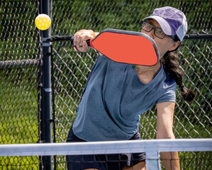 Female pickleball player prepares to block volley the pickleball