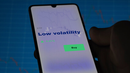 An investor's analyzing the low volatility etf fund on screen. A phone shows the ETF's prices stocks to invest