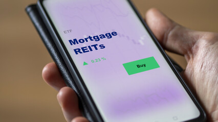 Mortgage REITs, An investor's analyzing the reit on screen. A phone shows the ETF's prices mortgages REITs