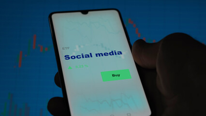 An investor's analyzing the social app on screen. A phone shows the ETF's prices social media