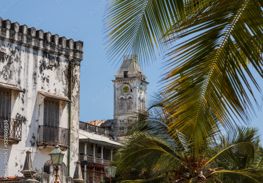 Wall mural tower with a clock in stone town and palm leaves. zanzibar, tanzania