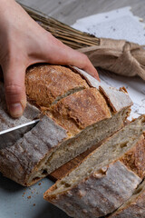 Persona cortando una barra de pan artesanal 