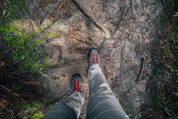 Top view of hiking shoes on a forest path. POV photo of hiking shoes on a dirt hiking trail.