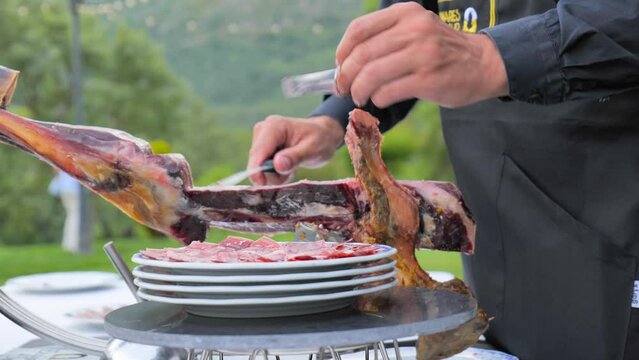 cutting slices of iberian ham in an elegant outdoor cocktail
