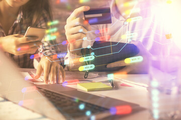 Double exposure of man and woman on-line shopping holding a credit card and data theme hologram drawing. Ai and E-commerce pay on-line concept.