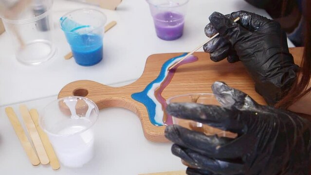 Epoxy resin art. Imitation of the sea. Sea foam. Modern trendy hobby. The pouring process of a wooden. Decorative cutting board. Master carpenter fills a wooden board with epoxy resin. Blue and white