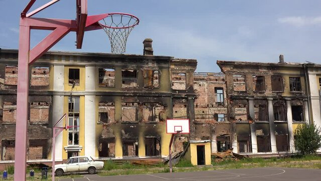 2022 - A badly damaged school building with basketball court foreground in Saltivka, Kharkiv, Ukraine.
