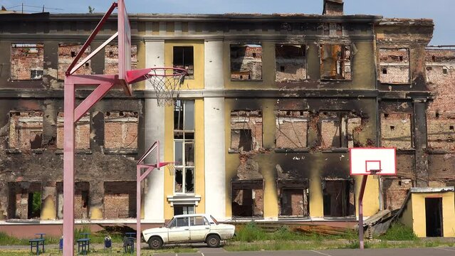 2022 - A badly damaged school building with basketball court foreground in Saltivka, Kharkiv, Ukraine.